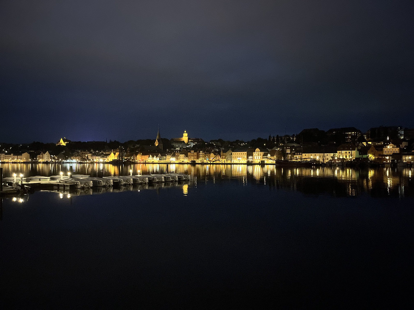 Flensburger Hafen bei Nacht mit beleuchteten Häusern und Spiegelungen im Wasser