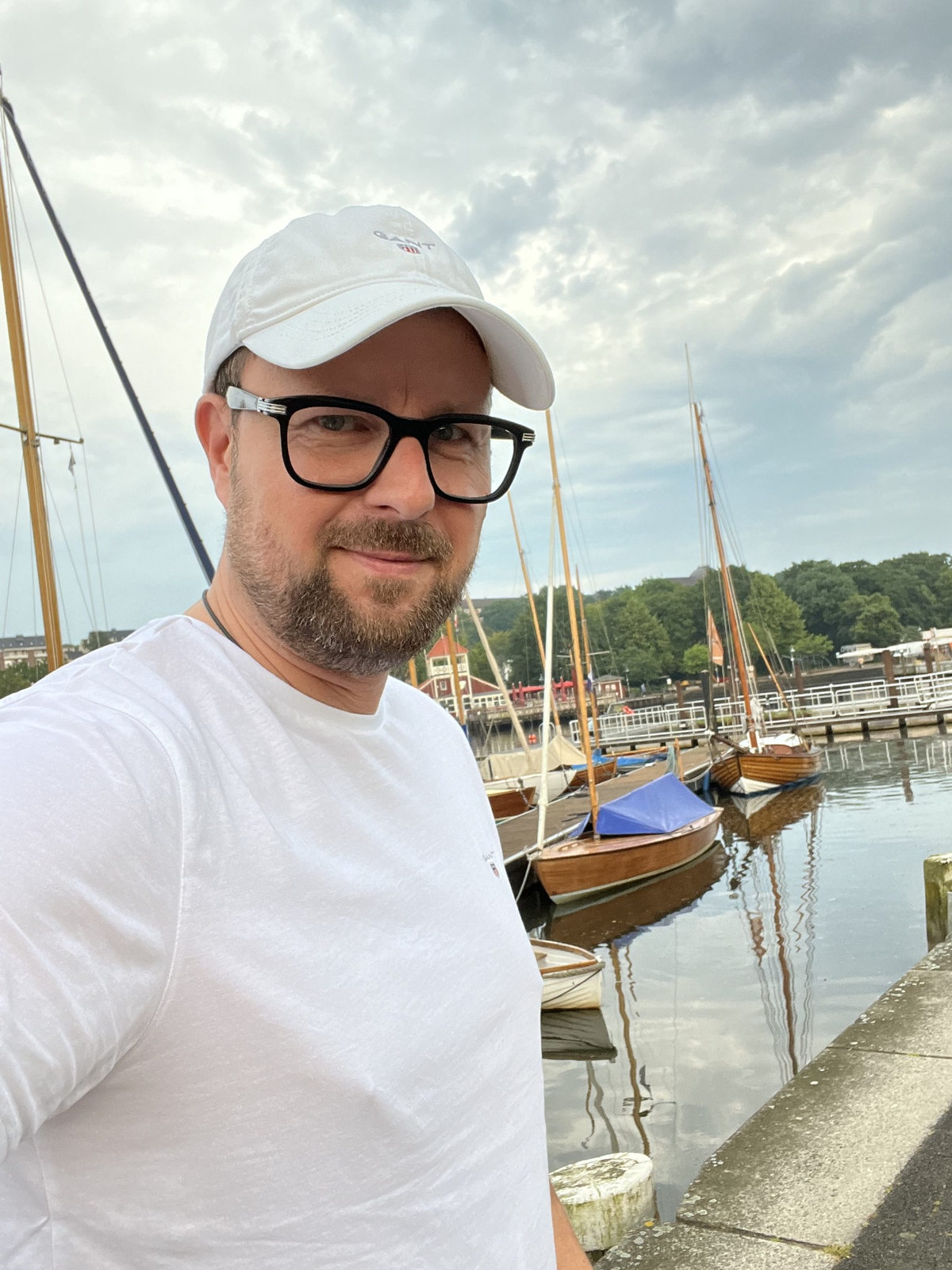 Steffen Günther mit weißer Kappe vor Segelbooten